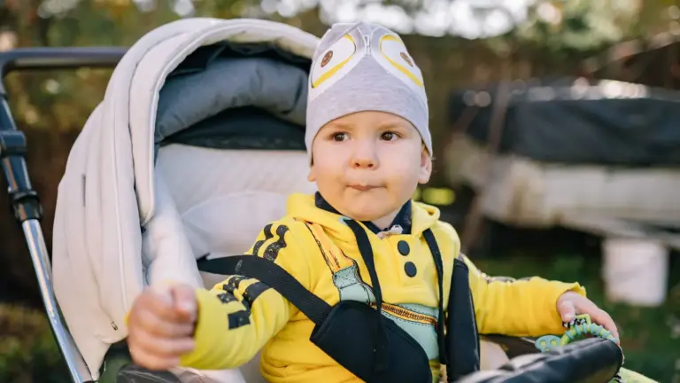 Baby mit gelber Jacke sitzt im Buggy